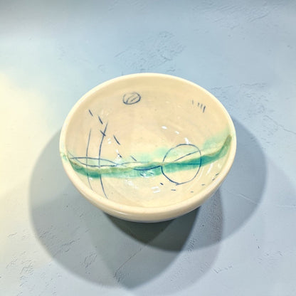 Small ceramic bowl with artistic design on a light blue background
