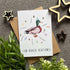 Greeting card with a duck illustration and text on a textured surface with decorative stars and plants.