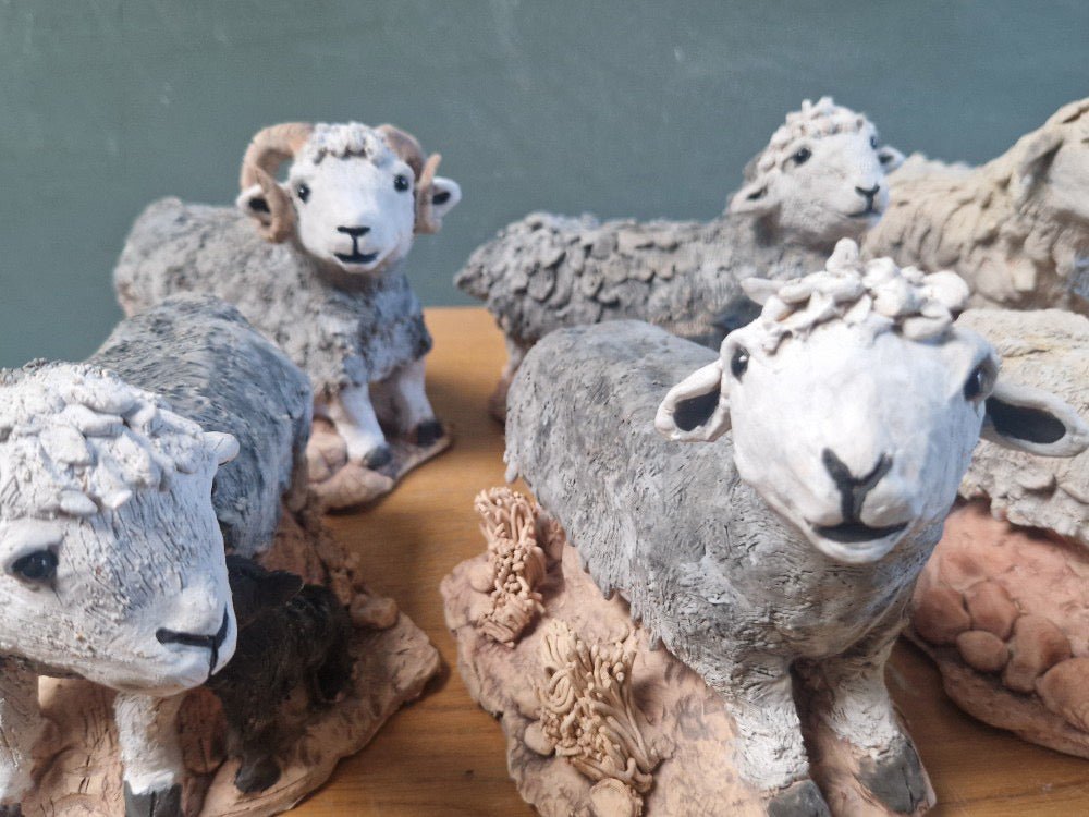 Collection of ceramic sheep figurines on a wooden surface with a green background