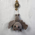 A crocheted bat hanging ornament in a medium gray color, featuring black embroidered eyes and a small pink nose, suspended from an antique bronze wall hook against a textured gray wall.
