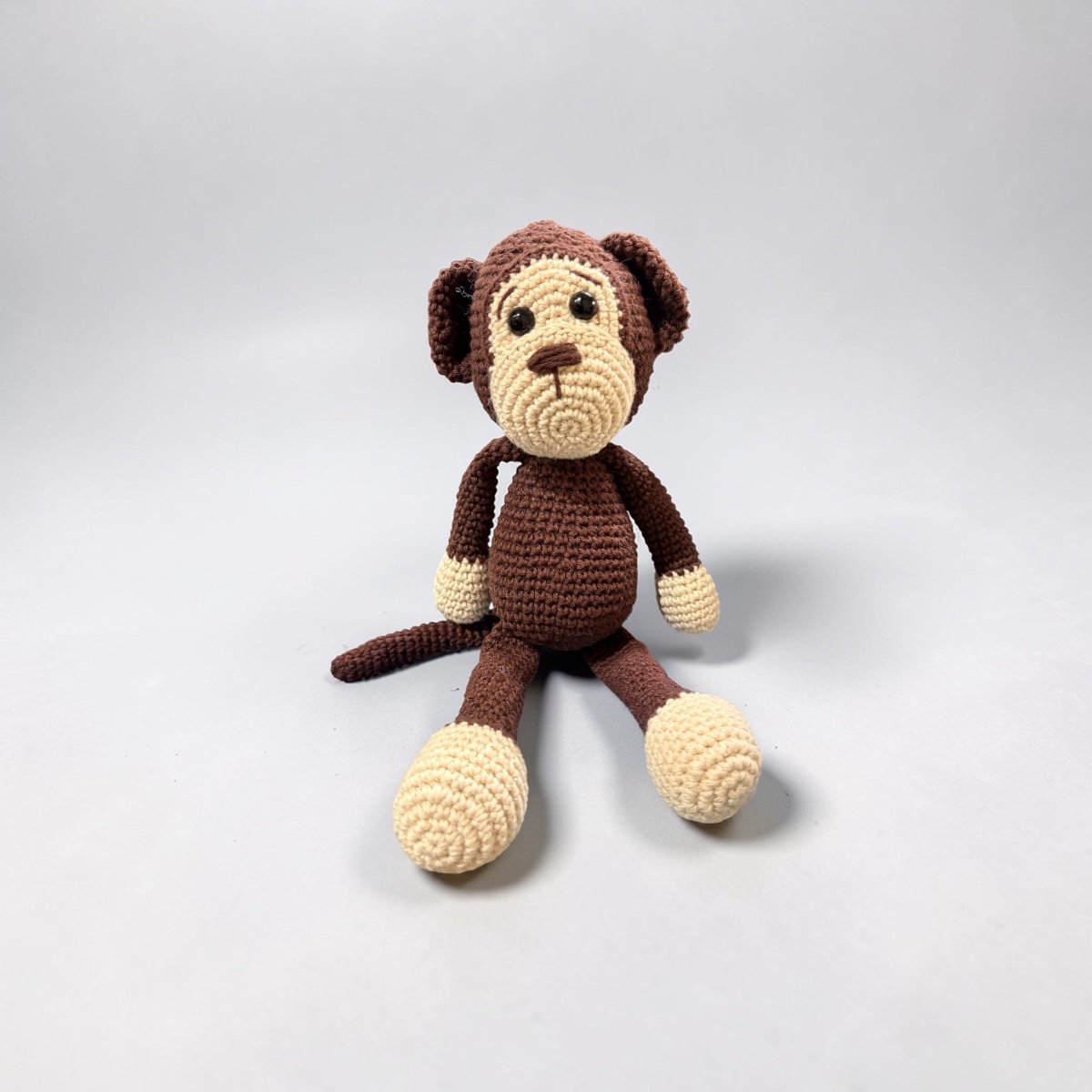 Crocheted monkey toy on a light gray background