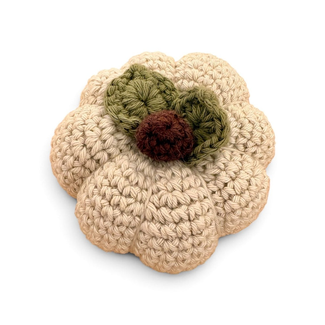 A crocheted pumpkin-shaped item in beige yarn with two olive green leaves and a dark brown stem, shown on a plain white background.