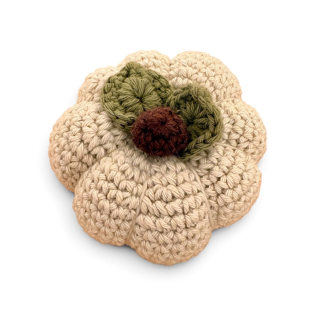 A crocheted pumpkin-shaped item in beige yarn with two olive green leaves and a dark brown stem, shown on a plain white background.
