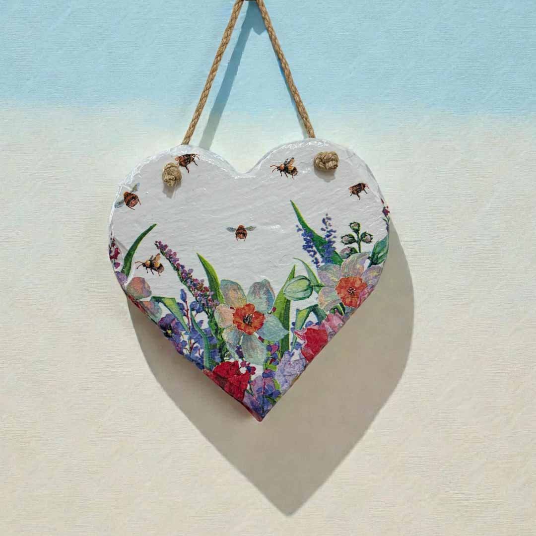 Heart-shaped wooden plaque with floral design hanging on a light blue and beige background