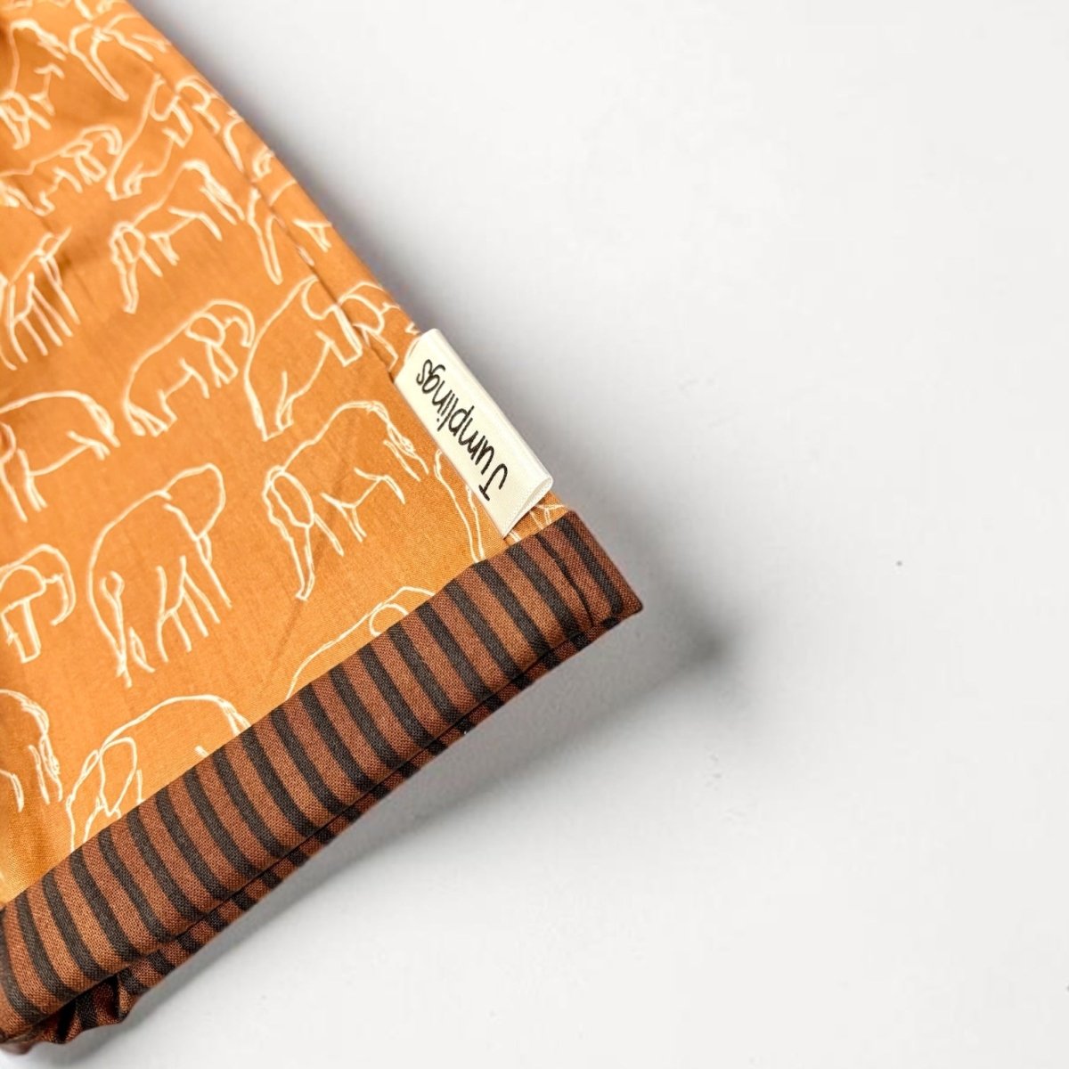 Folded fabric with elephant pattern and striped edge on a white background