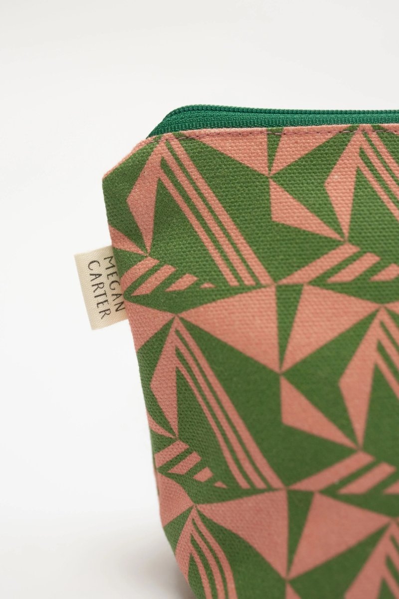 Green and pink geometric patterned pouch with a visible brand label on a white background