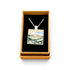 A square pendant necklace displayed in an open tan gift box with a black interior. The pendant features a colorful landscape painting with blue, green, yellow, and brown tones, suspended from a silver-toned chain.