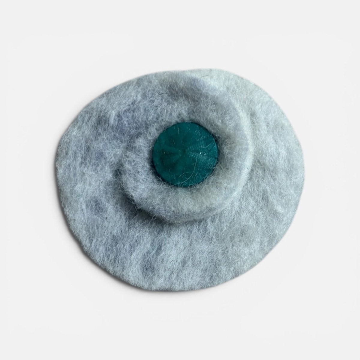Round gray felted product with a central teal circle on a light gray background