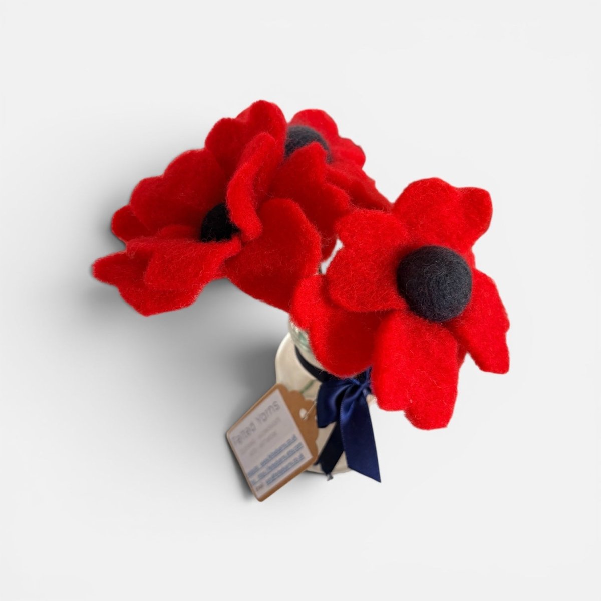 Red poppy flowers with a black center in a holder on a white background