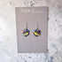 Colorful heart-shaped earrings on a Nancy Jones card against a marble background