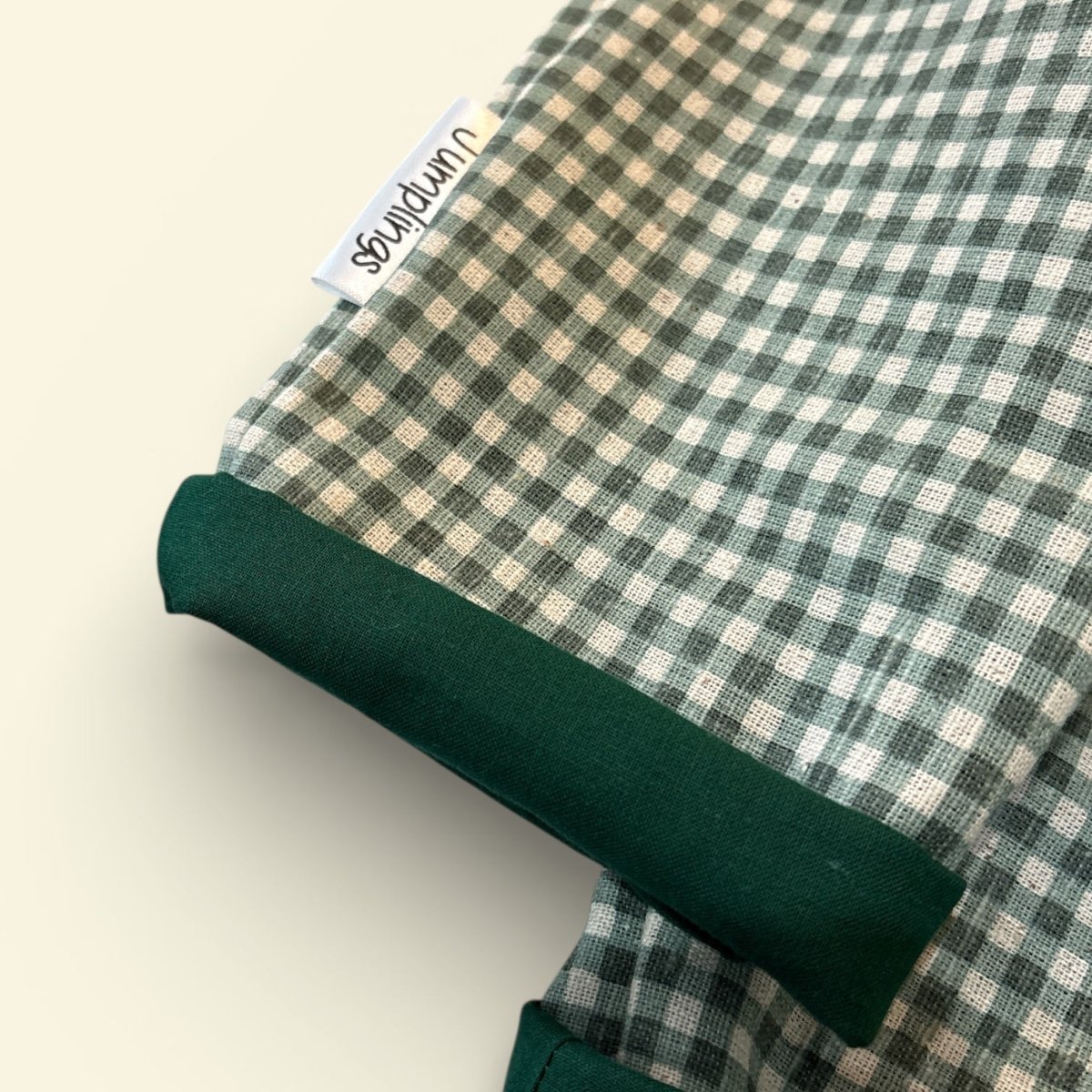 Green and beige checkered fabric with a visible brand tag on a light background