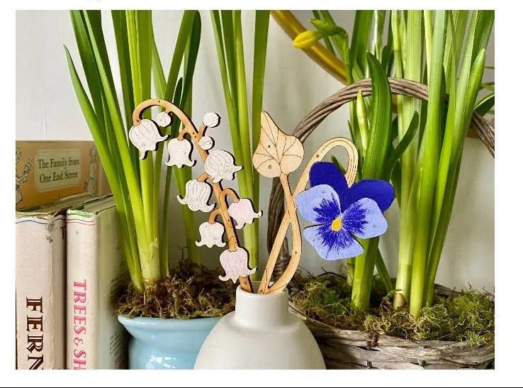 Decorative elements with hand-painted birchwood stems and a blue flower in a white vase.