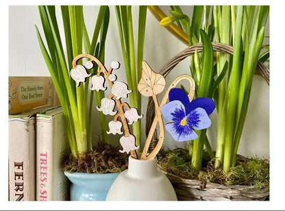 Decorative elements with hand-painted birchwood stems and a blue flower in a white vase.
