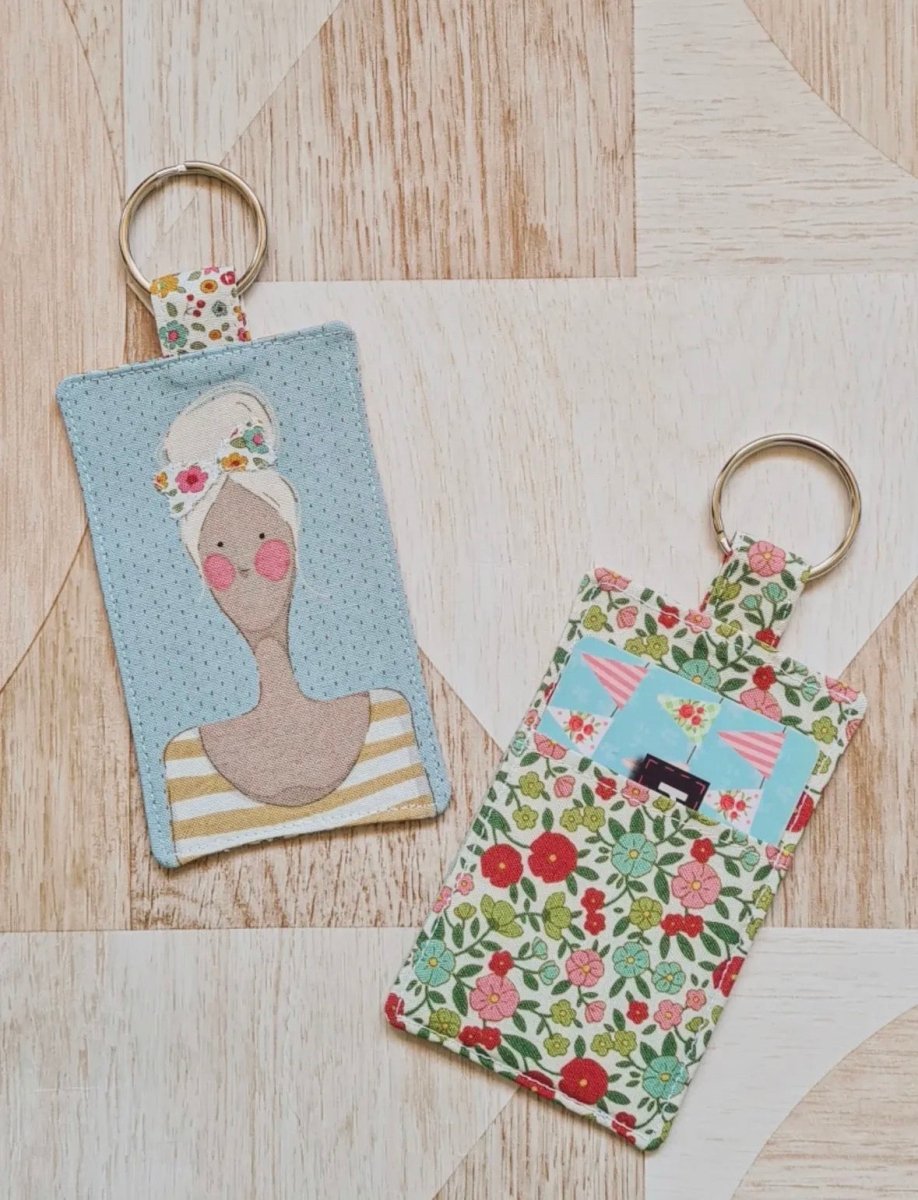 Two keychains on a wooden surface, one with a portrait design and the other with floral patterns.