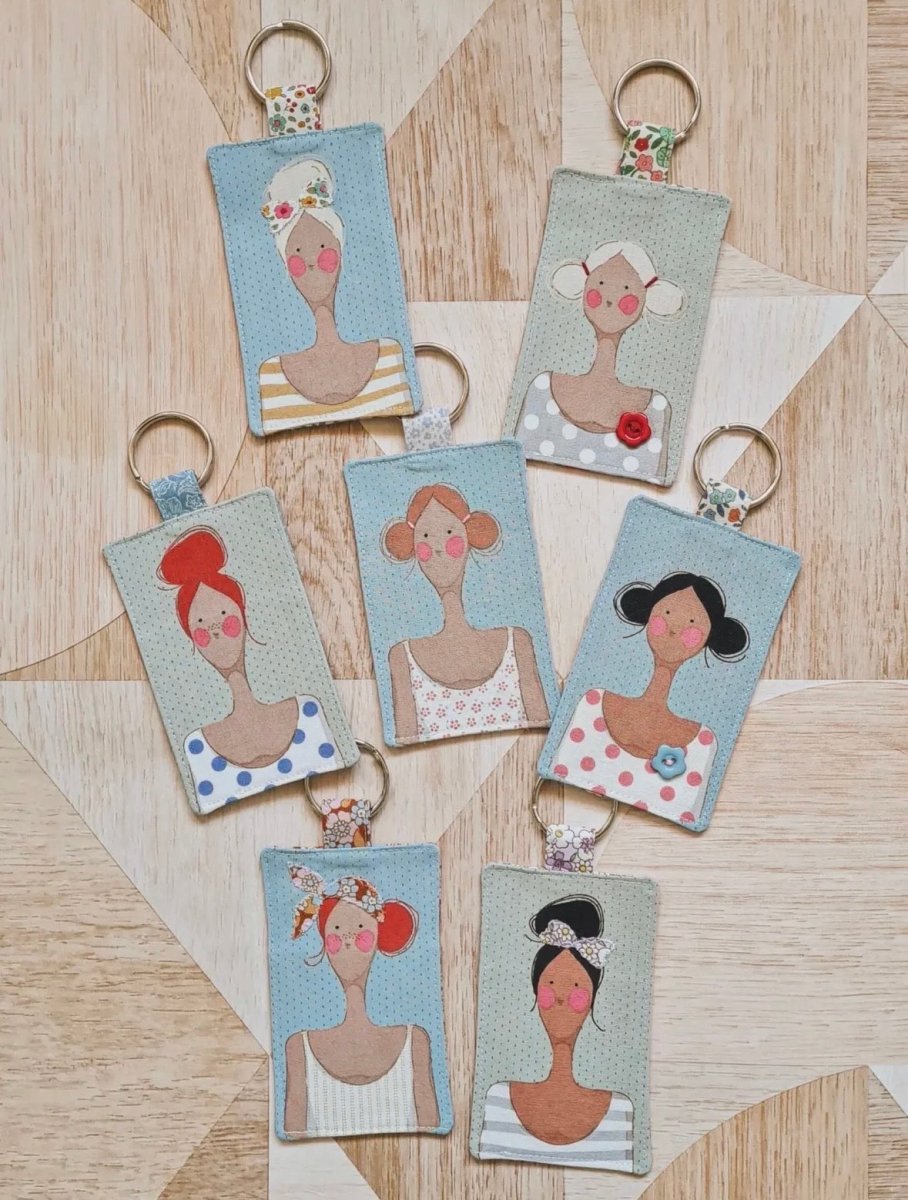 Set of keychains with illustrated portraits on a wooden surface