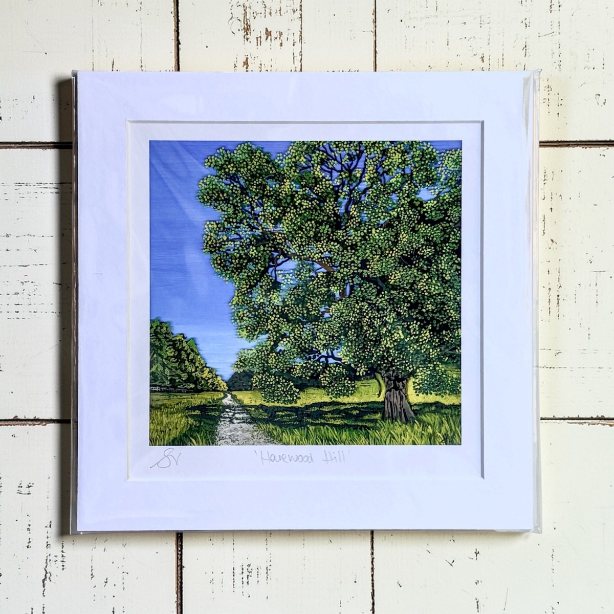 Framed artwork of a tree on a wooden surface