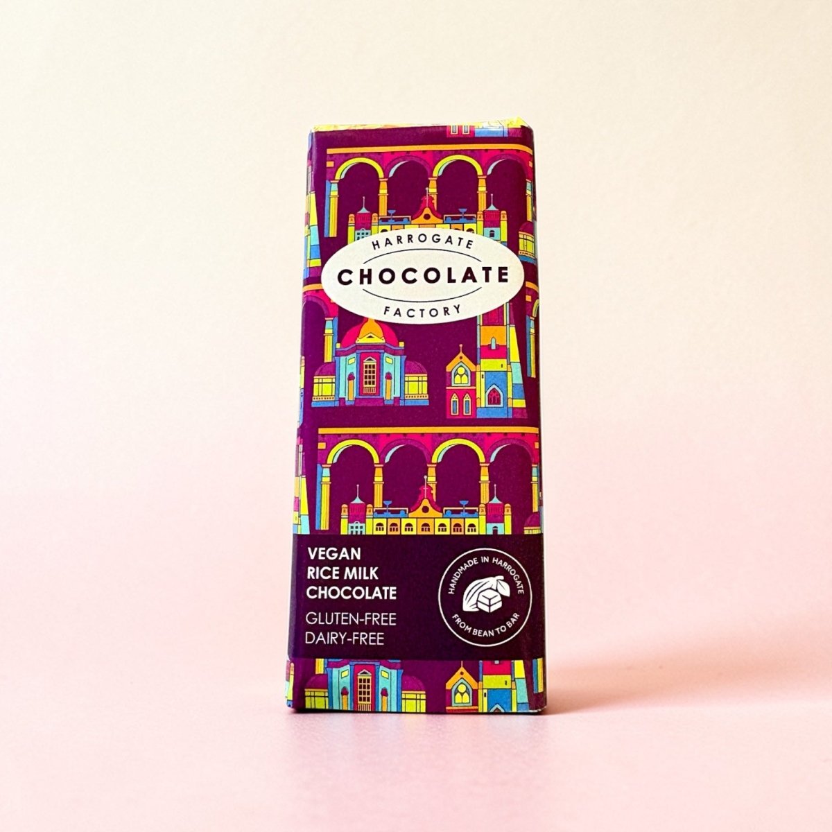 Vegan rice milk chocolate bar with colorful packaging on a light pink background