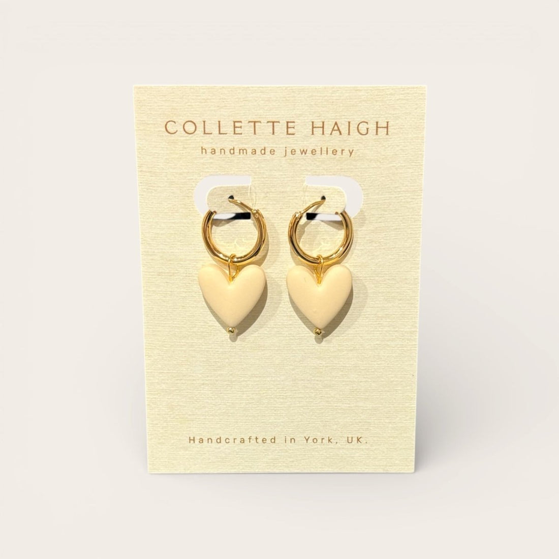 Heart-shaped earrings on a Collette Haigh branded card with a beige background