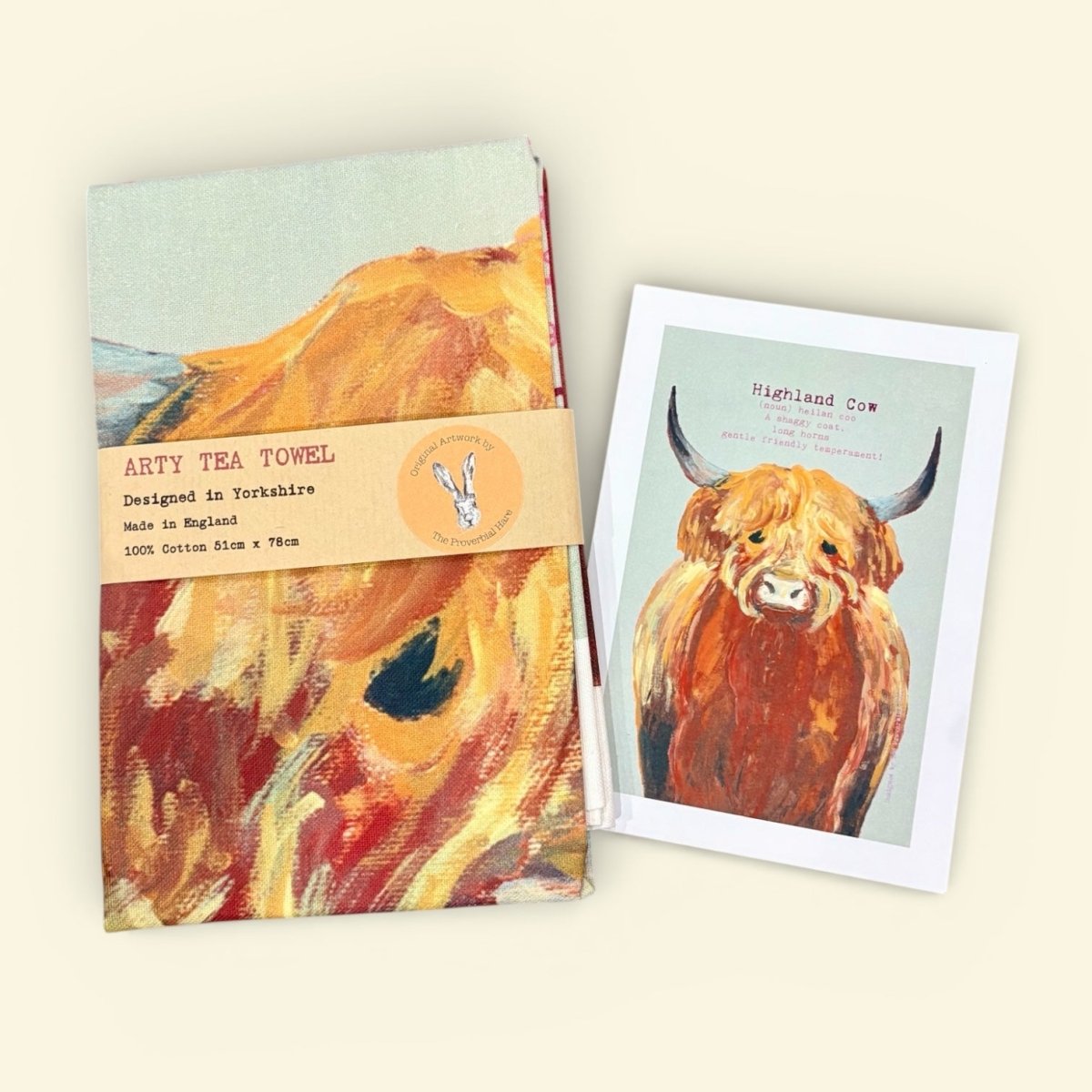 Tea towel with highland cow design and matching card on a light background