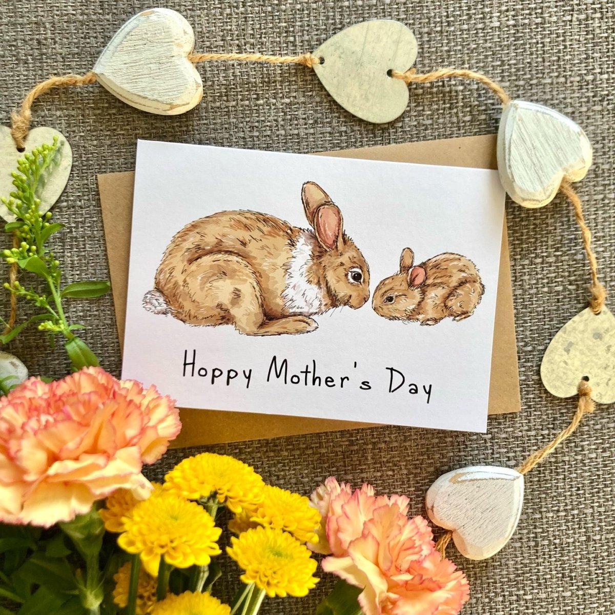 Mother's Day card with two bunnies and 'Happy Mother's Day' text, surrounded by flowers and heart decorations.