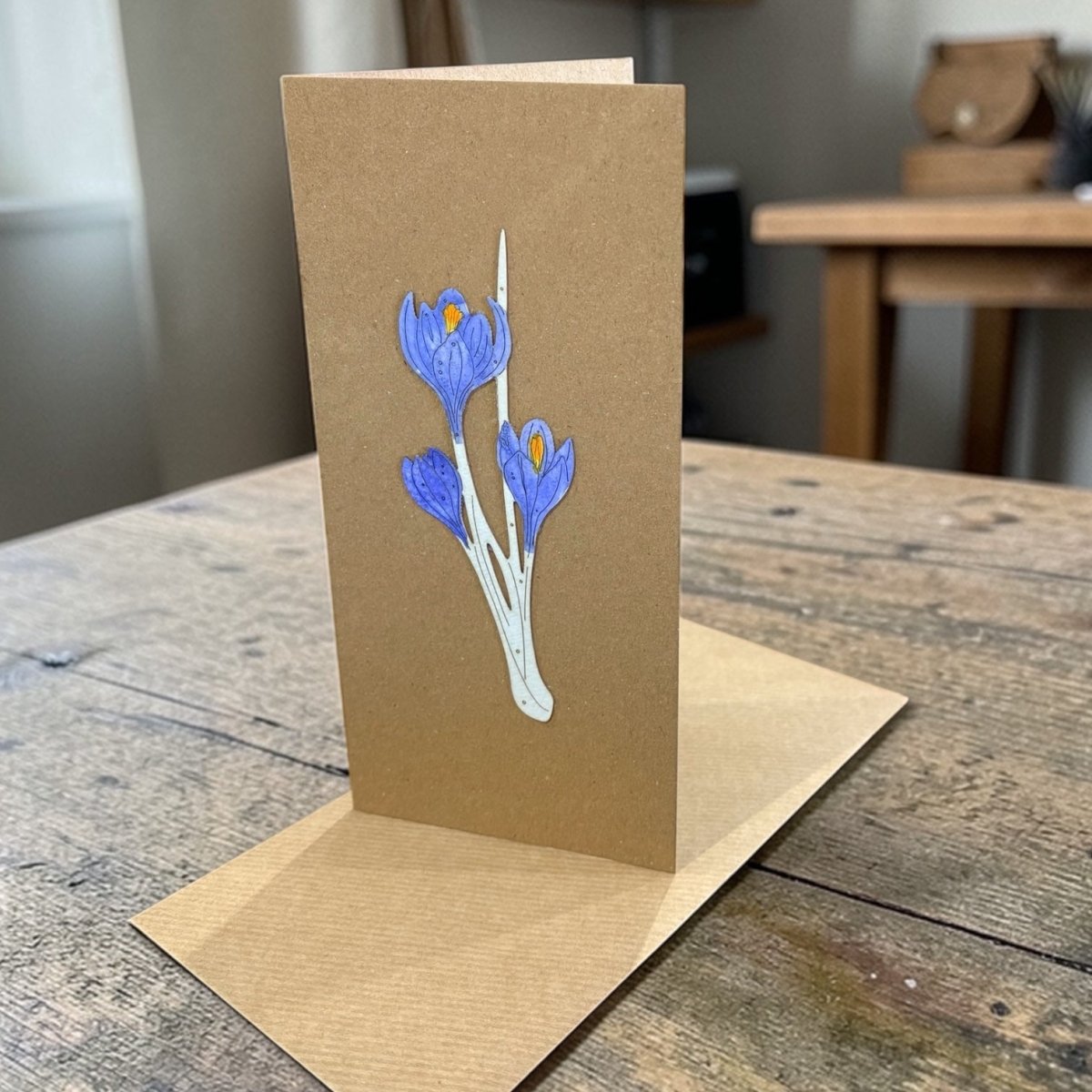 Brown greeting card with blue floral design on a wooden surface