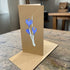 Brown greeting card with blue floral design on a wooden surface
