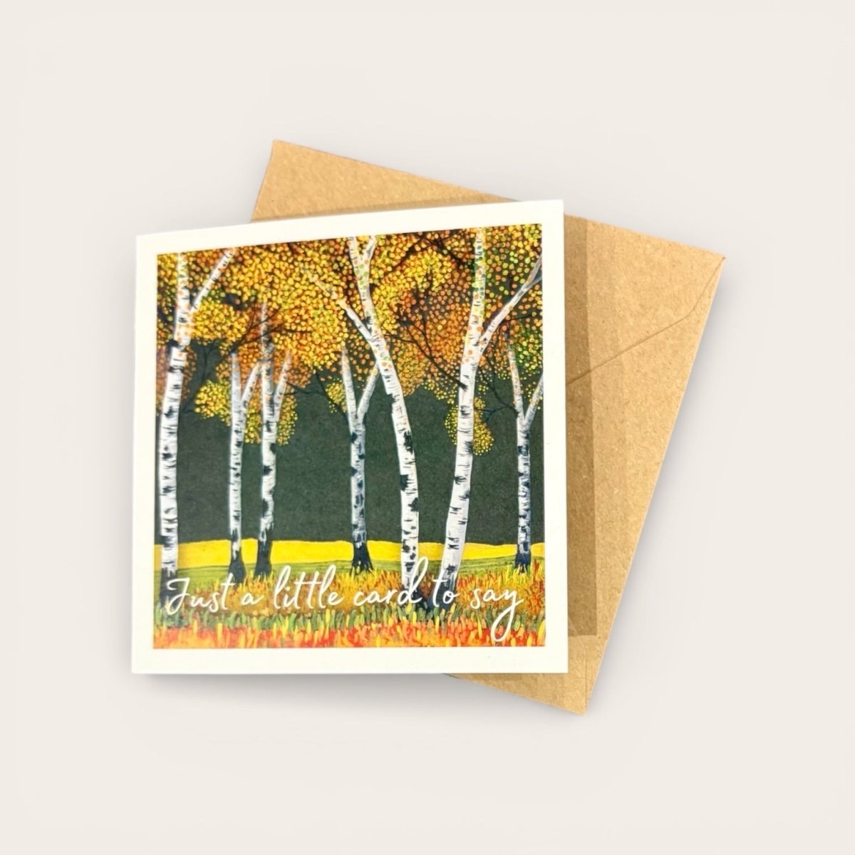 Greeting card with autumnal design of birch trees and a brown envelope on a light gray background