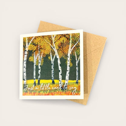Greeting card with autumnal design of birch trees and a brown envelope on a light gray background
