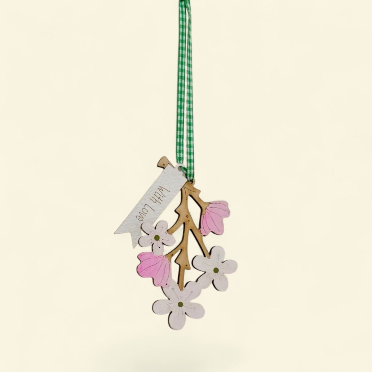 Decorative hanging ornament with flowers and a tag on a beige background