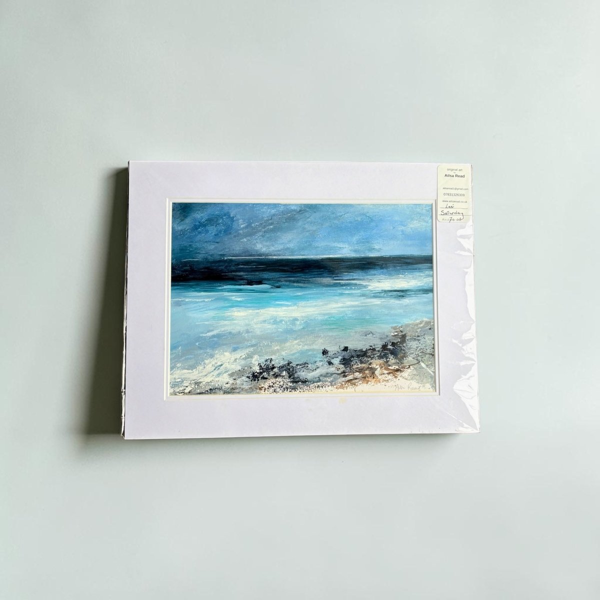 Framed artwork of a landscape with blue sky and water on a light gray background