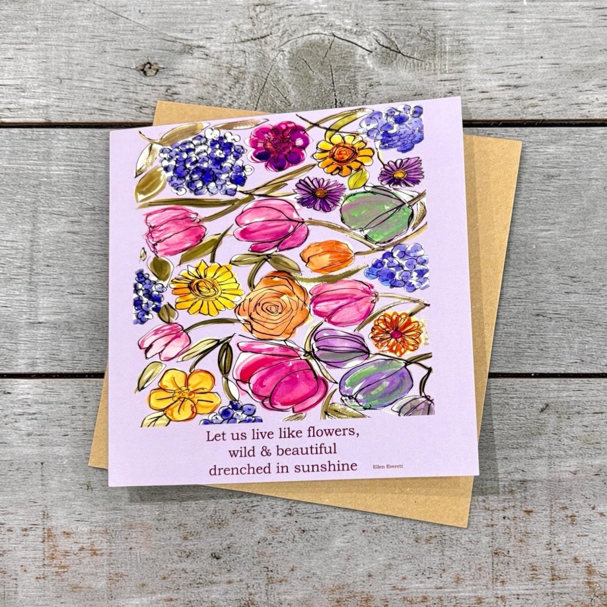 Greeting card with floral design and quote on a wooden surface