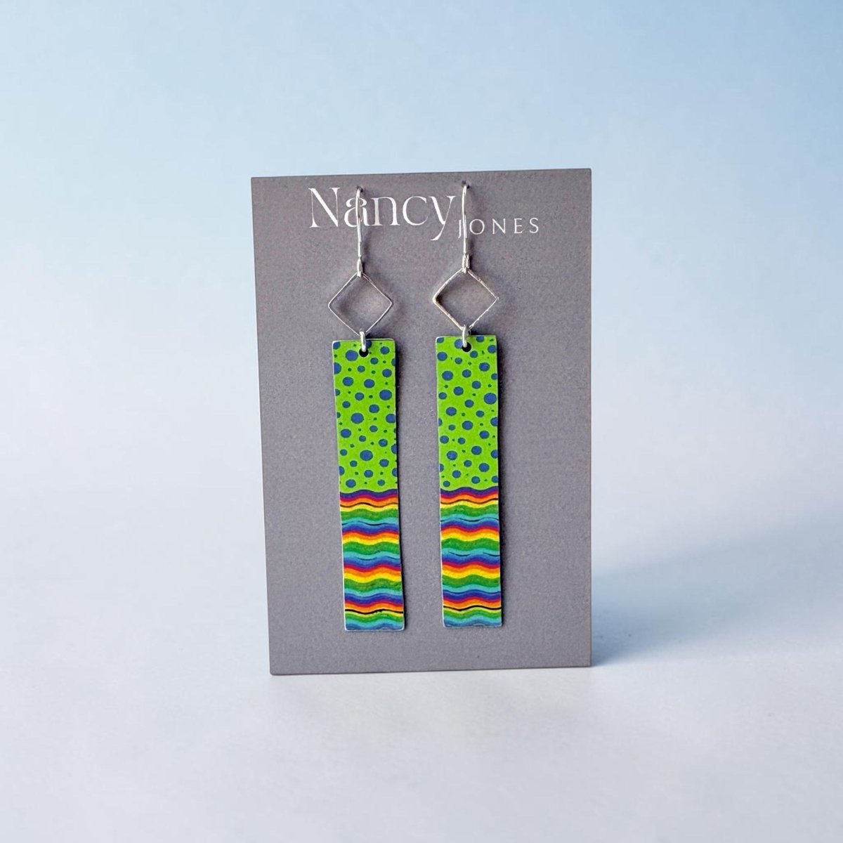 Pair of earrings with colorful patterns on a gray card with &