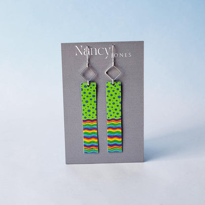 Pair of earrings with colorful patterns on a gray card with &