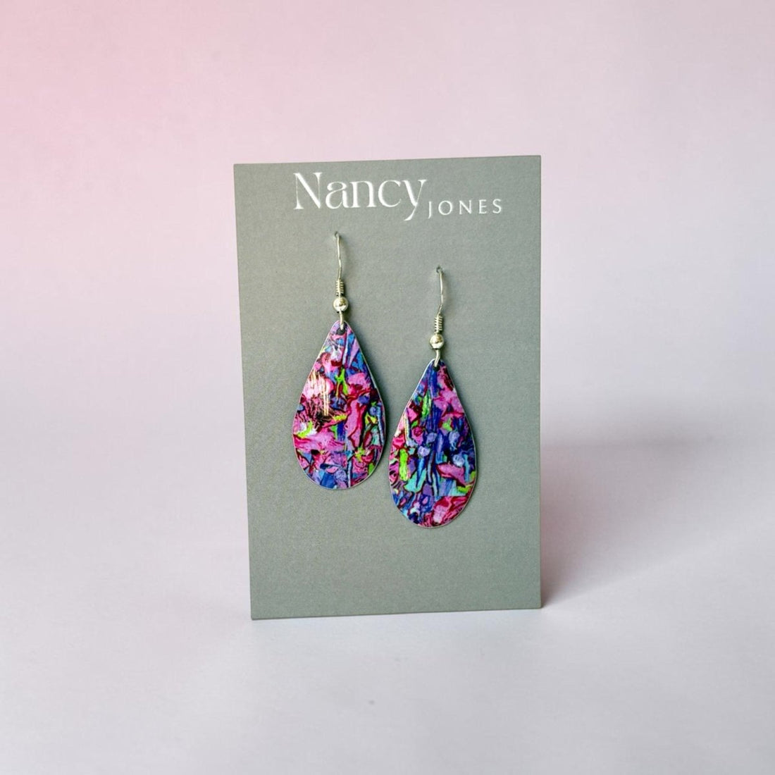 Colorful teardrop earrings on a Nancy Jones card against a light pink background