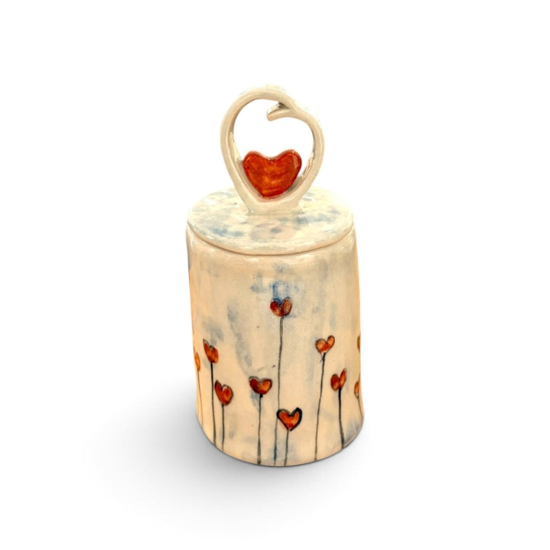A small cylindrical ceramic keepsake box with a lid, decorated with red heart flowers on a cream-colored glaze. The lid features a heart-shaped loop handle holding a red heart.