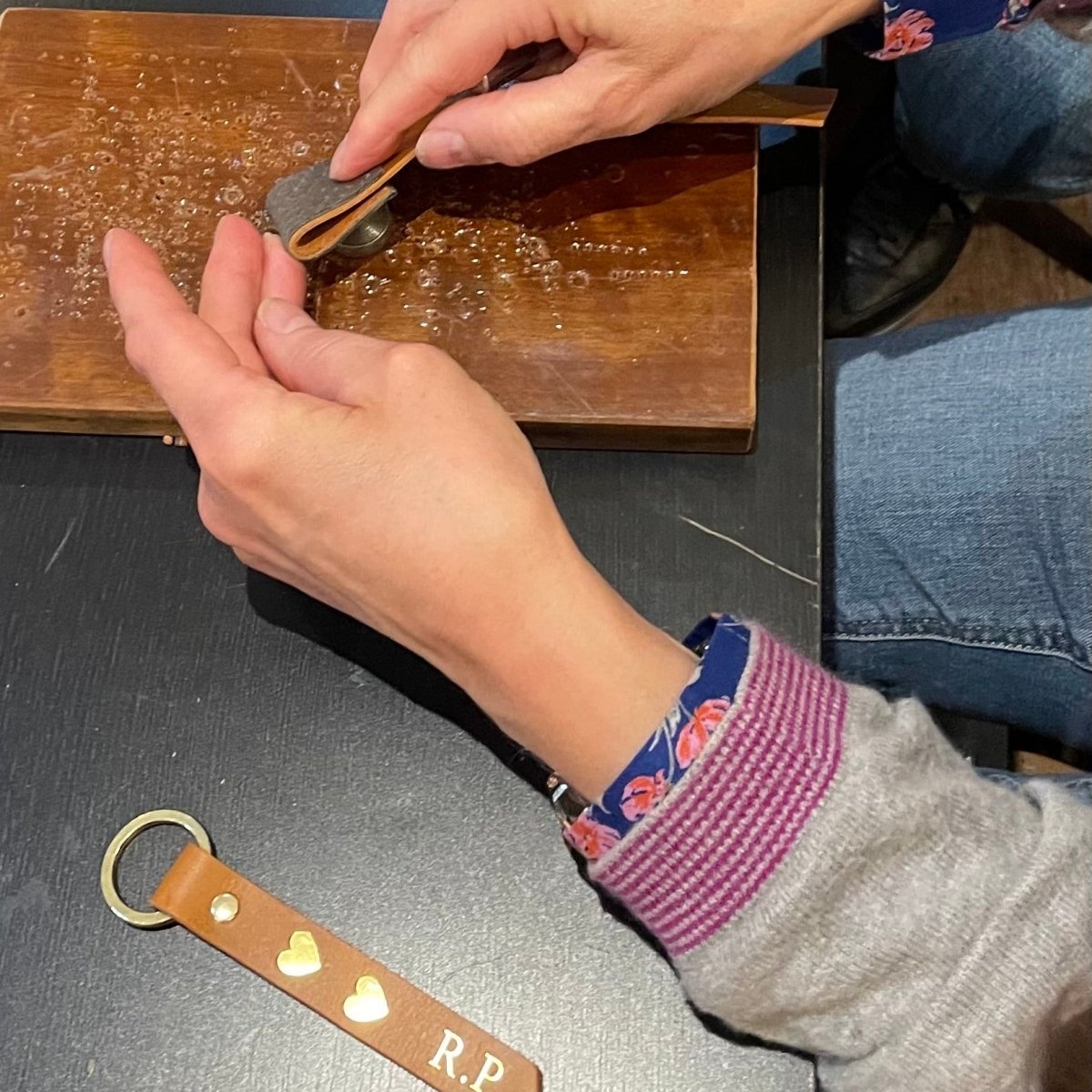 Person working on a leather project with tools and materials on a table.