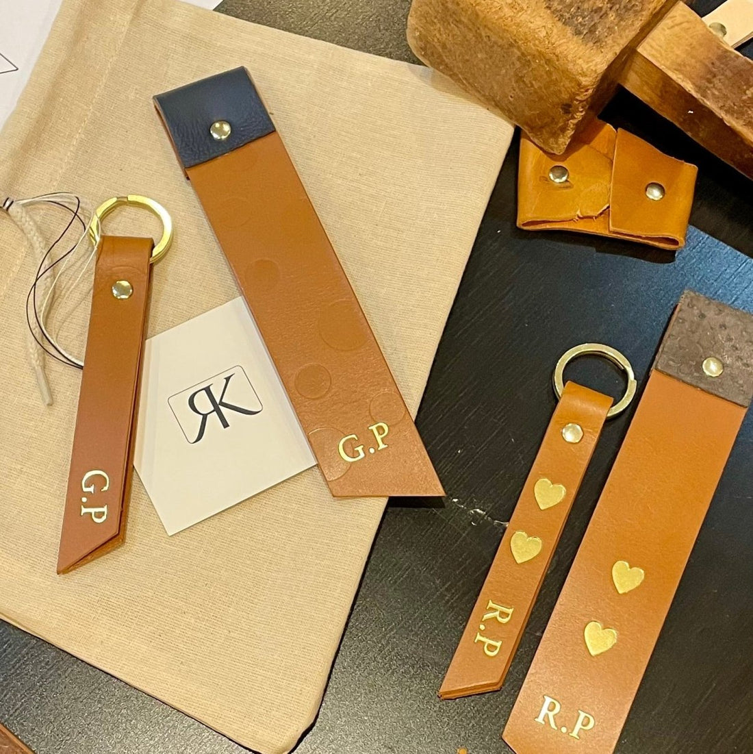 Collection of leather keychains and straps with initials on a wooden surface