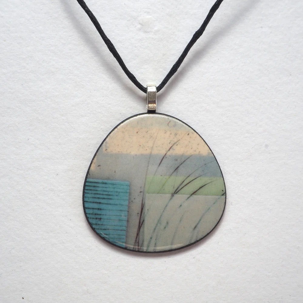 Round pendant with nature-inspired design on a white background