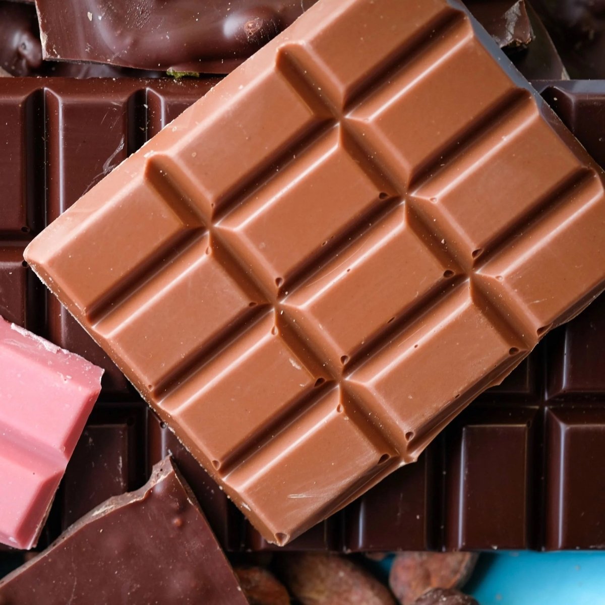 Close-up of a chocolate bar with a grid pattern on a background of various chocolates.