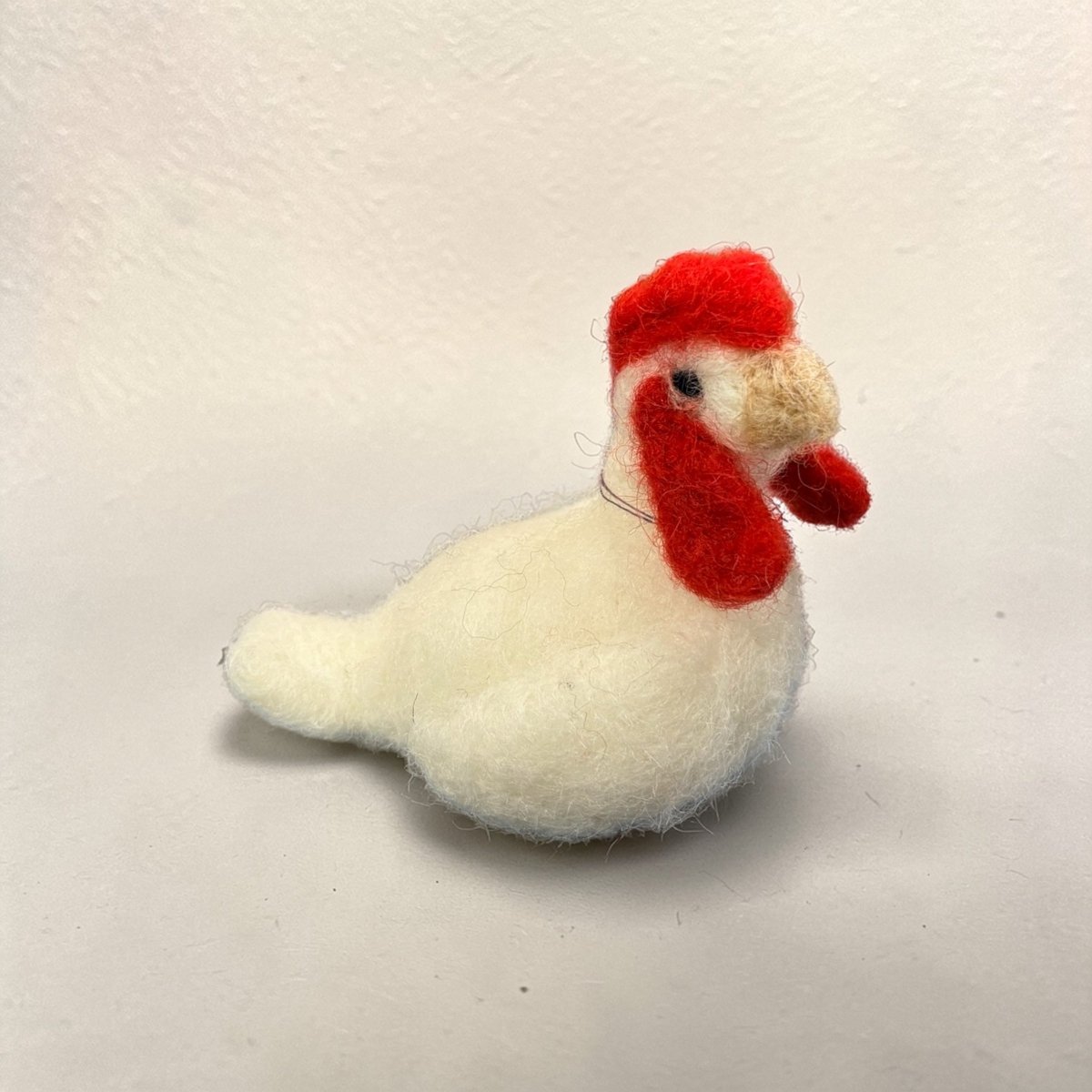 White rooster toy with red comb on a light gray background