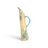 A tall, slender ceramic pitcher with a curved handle, featuring a cream-colored glaze decorated with turquoise blue floral and scroll patterns and small orange accents, set against a plain white background.
