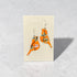Orange bird-shaped earrings on a Nancy Jones card against a gray background