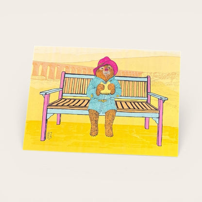 Illustration of a teddy bear sitting on a bench with a colorful background