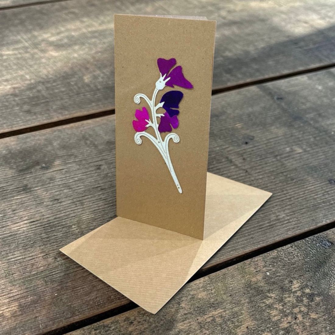 Brown greeting card with floral design on a wooden surface