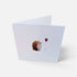 A folded white greeting card standing open on a light gray background, featuring a small watercolor illustration of a hedgehog holding a red balloon.