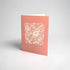 Pink greeting card with white floral design and &