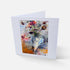 A white greeting card standing upright, featuring an abstract floral painting in the center with a white border, photographed on a light gray background.