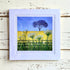 Framed artwork of a tree and flowers on a wooden surface