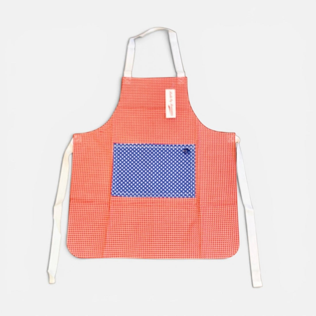 A red and white gingham apron with a blue and white polka dot pocket on the front, featuring white neck and waist ties, shown against a light gray background.
