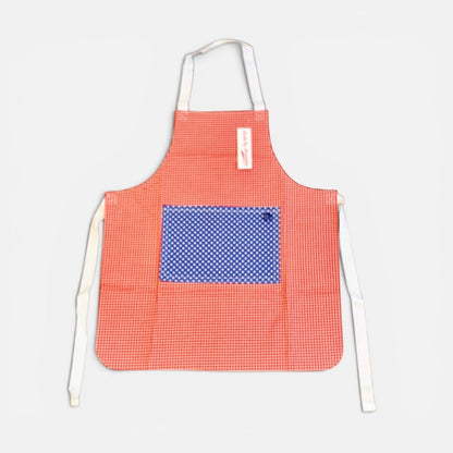 A red and white gingham apron with a blue and white polka dot pocket on the front, featuring white neck and waist ties, shown against a light gray background.